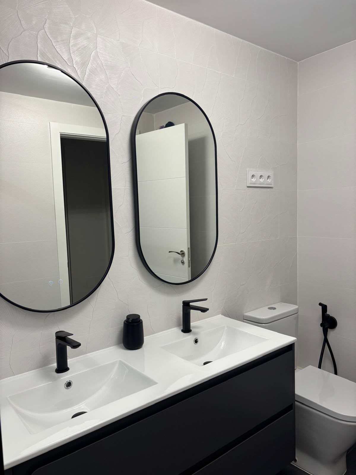 Baño rehabilitado con doble lavabo y espejos ovalados